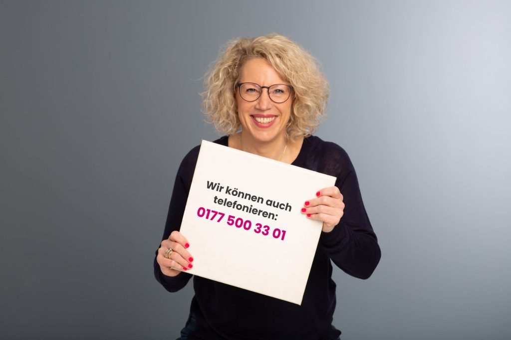 Simone Mortensen hält ein Schild: Wir können auch telefonieren: 0177 500 33 01